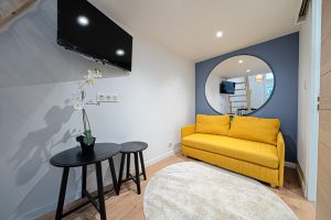 Salon rénové sous la mezzanine avec un canapé jaune